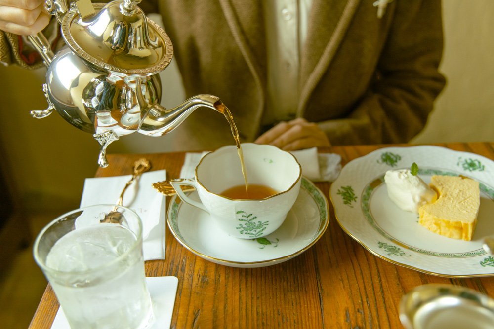 ティーポットから紅茶を注ぐ様子とケーキ